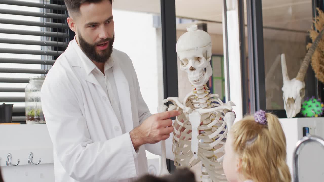 un maestro masculino diverso y escolares felices estudiando el esqueleto en la clase de biología