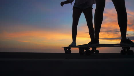 skateboarding on a road at sunset, two friends create a mesmerizing scene in slow motion with mountains and a beautiful sky. they're attired in shorts