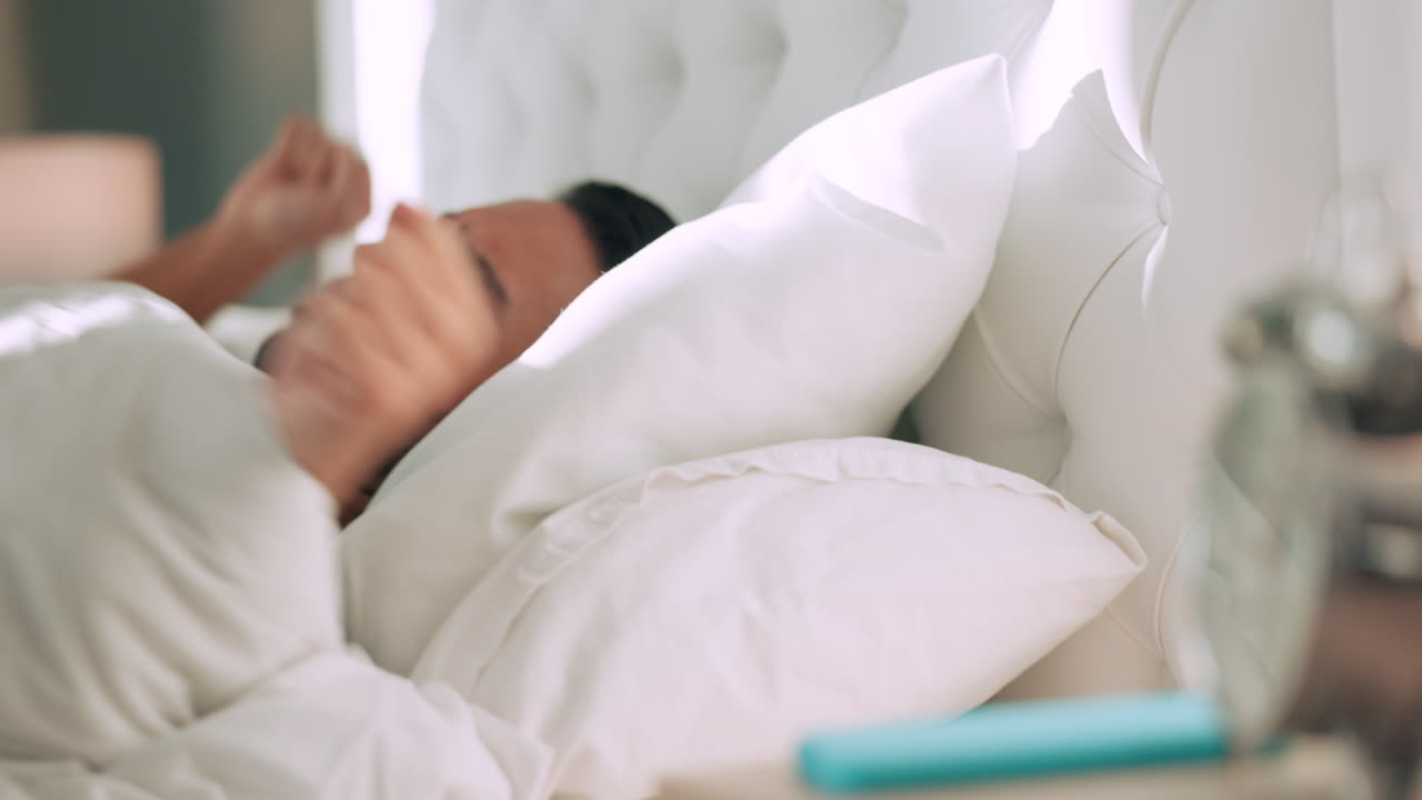 깨어나기 위해 알람 시계와 함께 침대에서 피곤한 사람