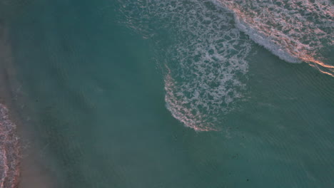 Toma-Aérea-De-Arriba-Hacia-Abajo-De-Olas-En-Un-Océano-Azul-Cristalino-Con-Playa-De-Arena-Blanca-En-Cancún,-México