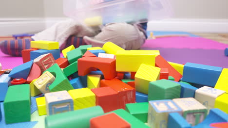 toddler boy dumping a container of colorful blocks on to the floor