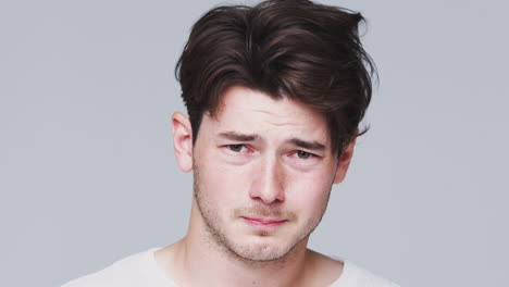 head and shoulders studio shot of unhappy man looking at camera with sad expression in slow motion