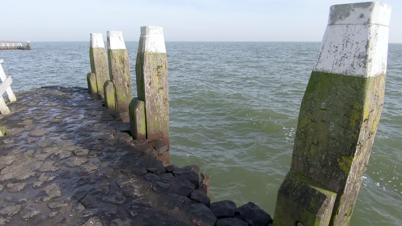 vista al mar desde un muelle de piedra con barandilla de madera y bolardos