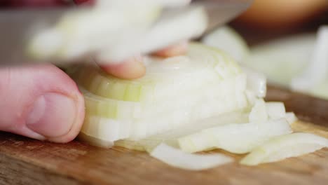 male hand with a knife cut the onion into pieces.