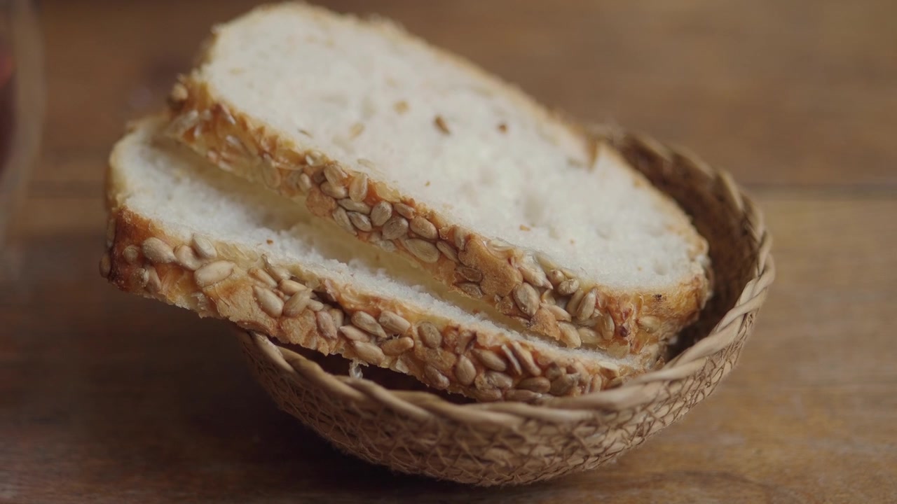 Hand nimmt ein Stück Sonnenblumenkernbrot aus einem geflochtenen Korb
