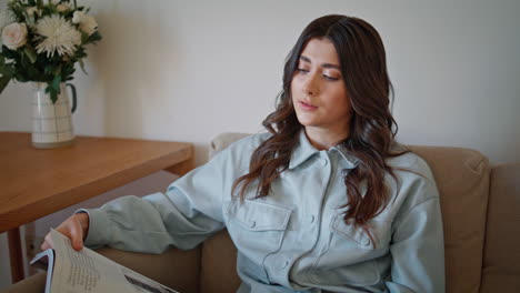 housewife looking magazine resting couch at home alone closeup. woman morning
