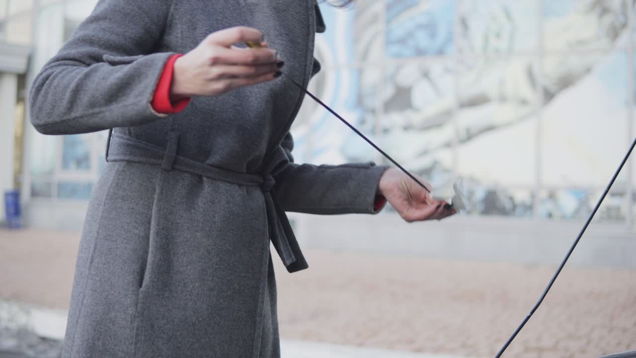 사업가 여성은 거리에서 후드  ⁇ 을 살펴 차의 오일 레벨을 확인합니다. 다이프 스틱을 꺼내