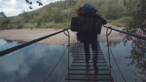 person hiking over a suspension bridge in nature