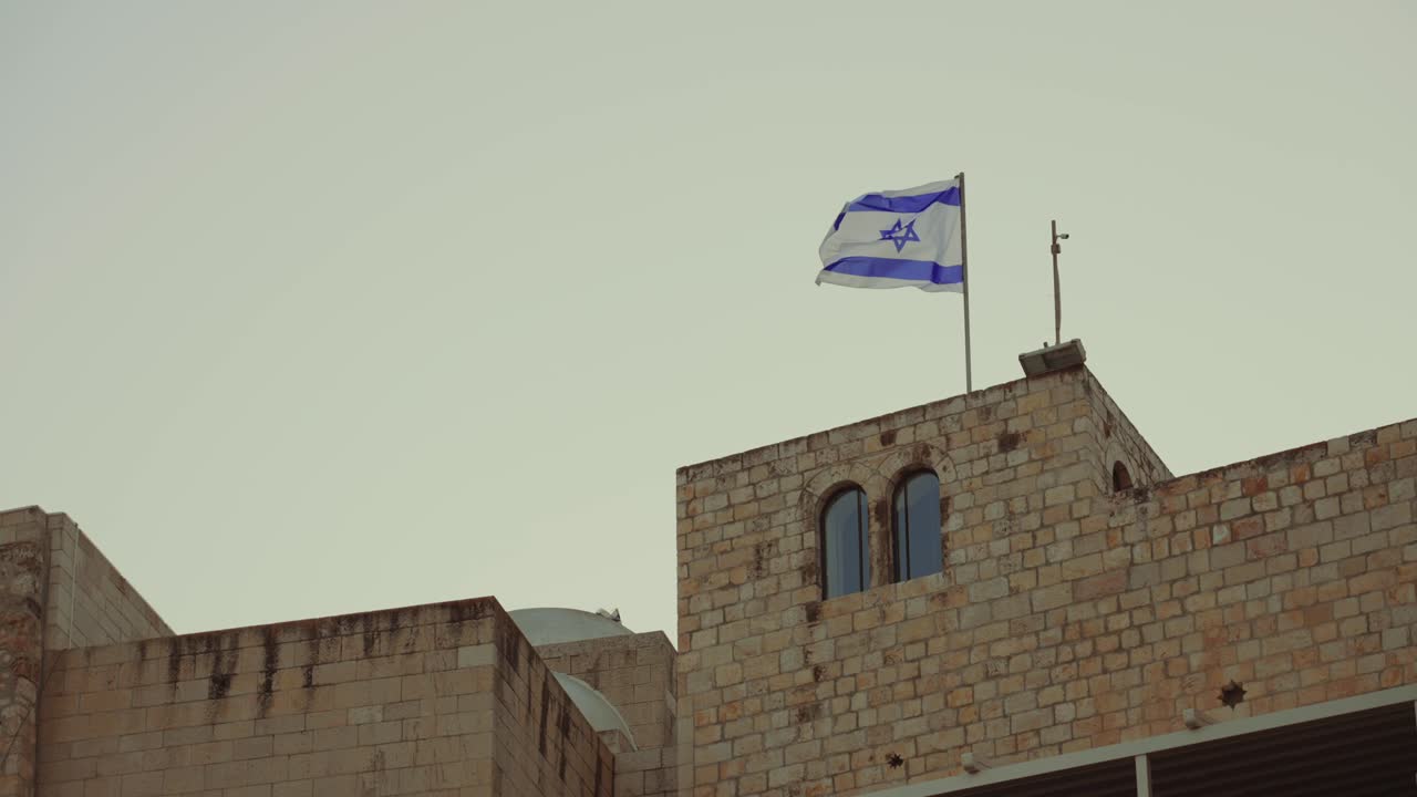 イスラエルの国旗は、古い古代都市の西の嘆きの壁の近くの聖地エルサレムの上にはためきます