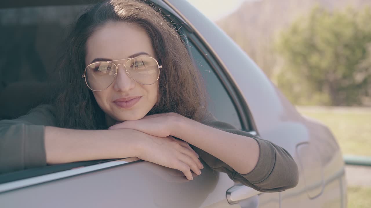 안경을 입은 예쁜 여자가 현대 자동차 창문 밖으로 기울어져 있습니다.