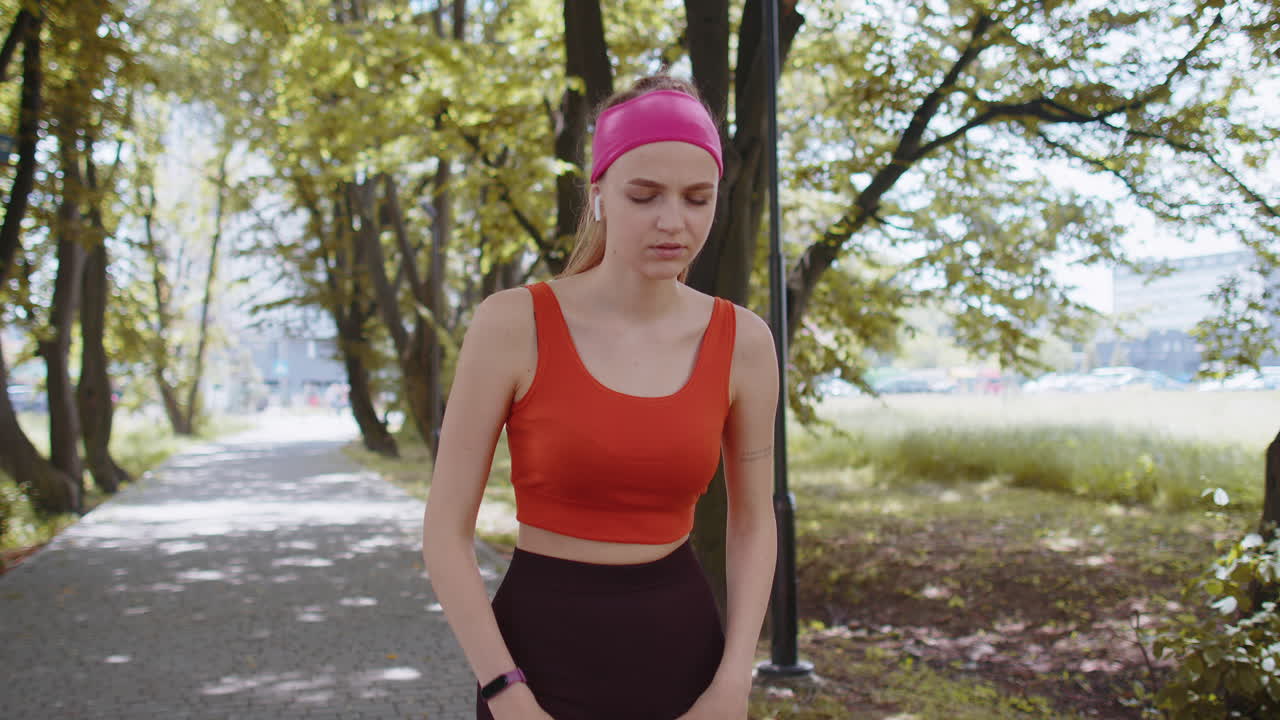 corredora deportiva cansada después de un entrenamiento de jogging, terminando la carrera en el parque