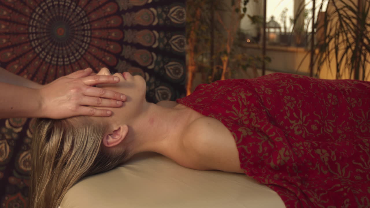 Masseuse massaging the back and neck of a woman lying on a massage bed. Performs a relaxing lomi lomi massage in the wellness salon. Caring for a healthy mind and body