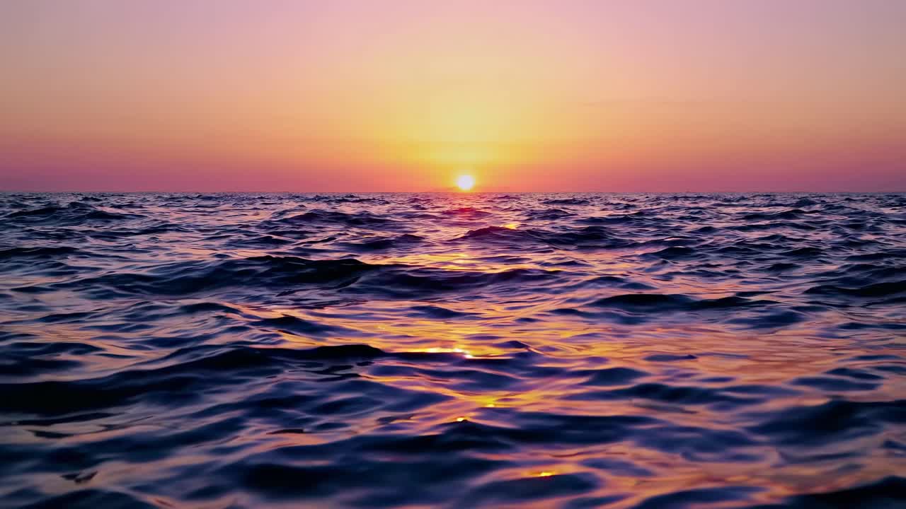 A serene sunset over the ocean with gentle waves, captured from a low-angle perspective