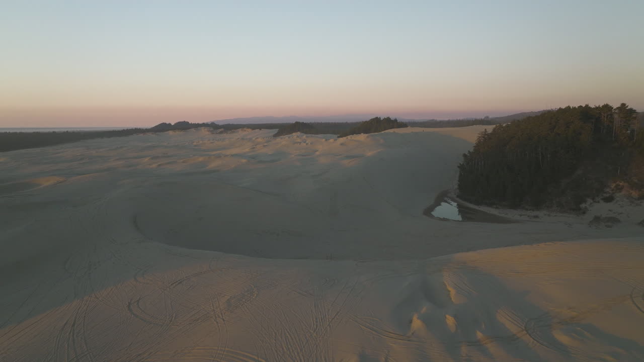 Golden hour light on sand dunes of Dunes City, Oregon, low flyover, setting used as inspiration for Dune films.