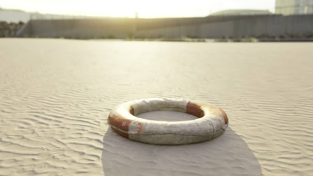 Lifebuoy resting on sandy surface at sunset near shoreline