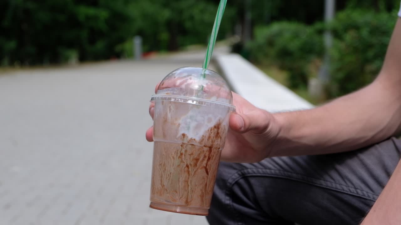 Man holding a paper milkshake cup in hands