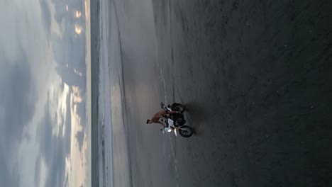 antena de formato vertical de barrido: motociclistas en la arena de la playa