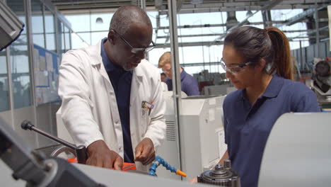 engineer teaching apprentice how to use machine in factory