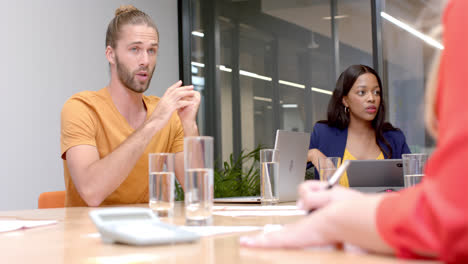 Caucasian-casual-businessman-talking-to-diverse-colleagues-at-office-meeting