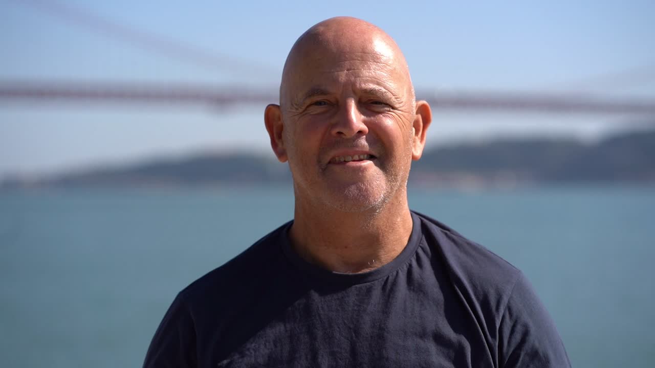 Retrato de homem idoso feliz parado à beira do rio