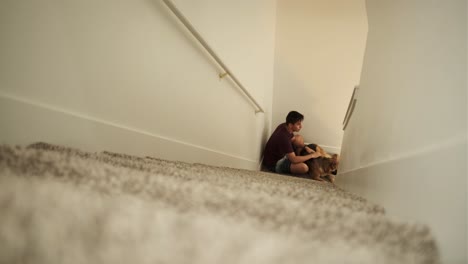 Young-Man-Plays-and-Cuddles-with-Large-German-Shepherd-dog-at-bottom-of-stairway