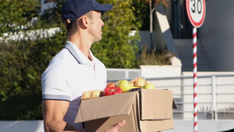 â€“â°ourier in uniform with package of fruits walking down street