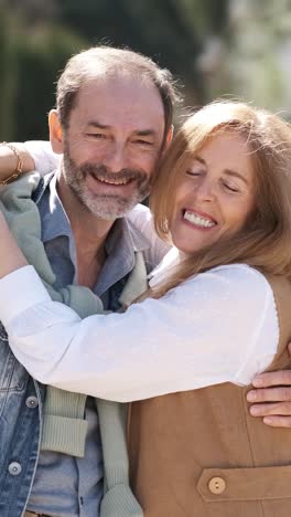 happy mature couple hugging in city park. vertical footage