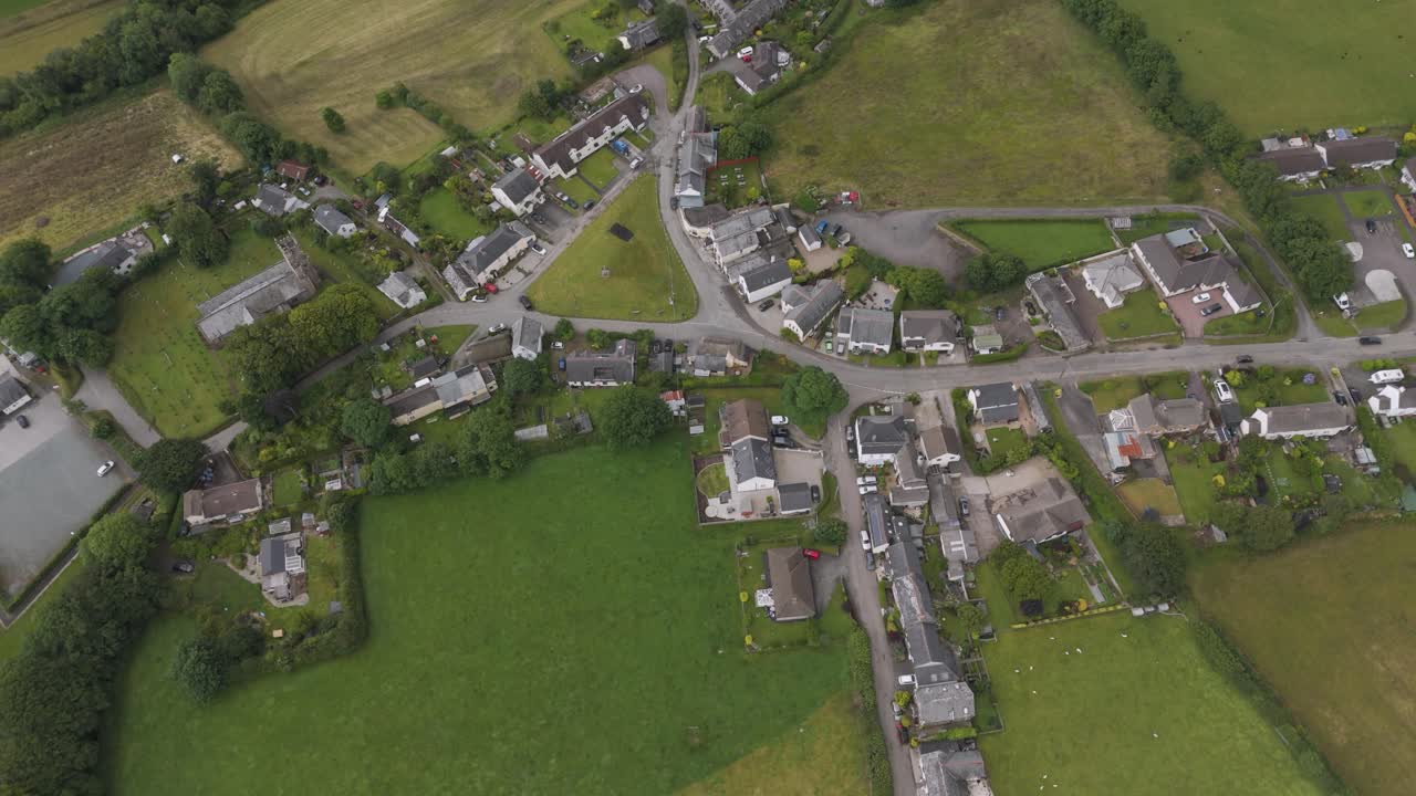 Aerial view of a rural village with houses, roads, and green fields