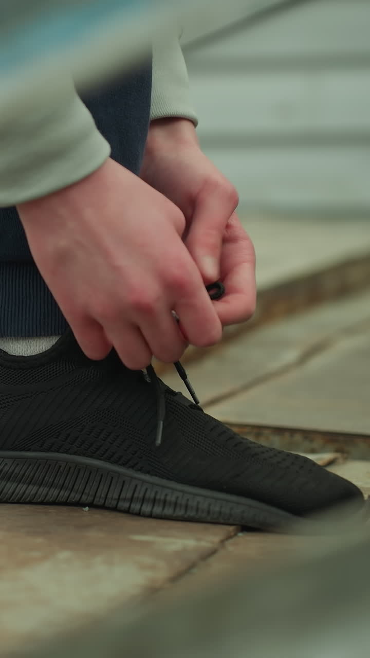 녹은 계단에서 신발을 는 누군가의 클로즈업, 배경에서 걸어가는 갈색 스웨터를 입은 누군가의 흐릿한 시각