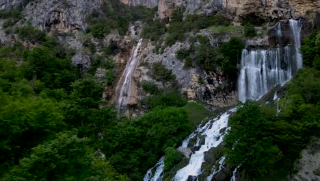 aerial forward view ujevara e sotires wild waterfalls in nivica canyon with cliffs of karst gorge with pool