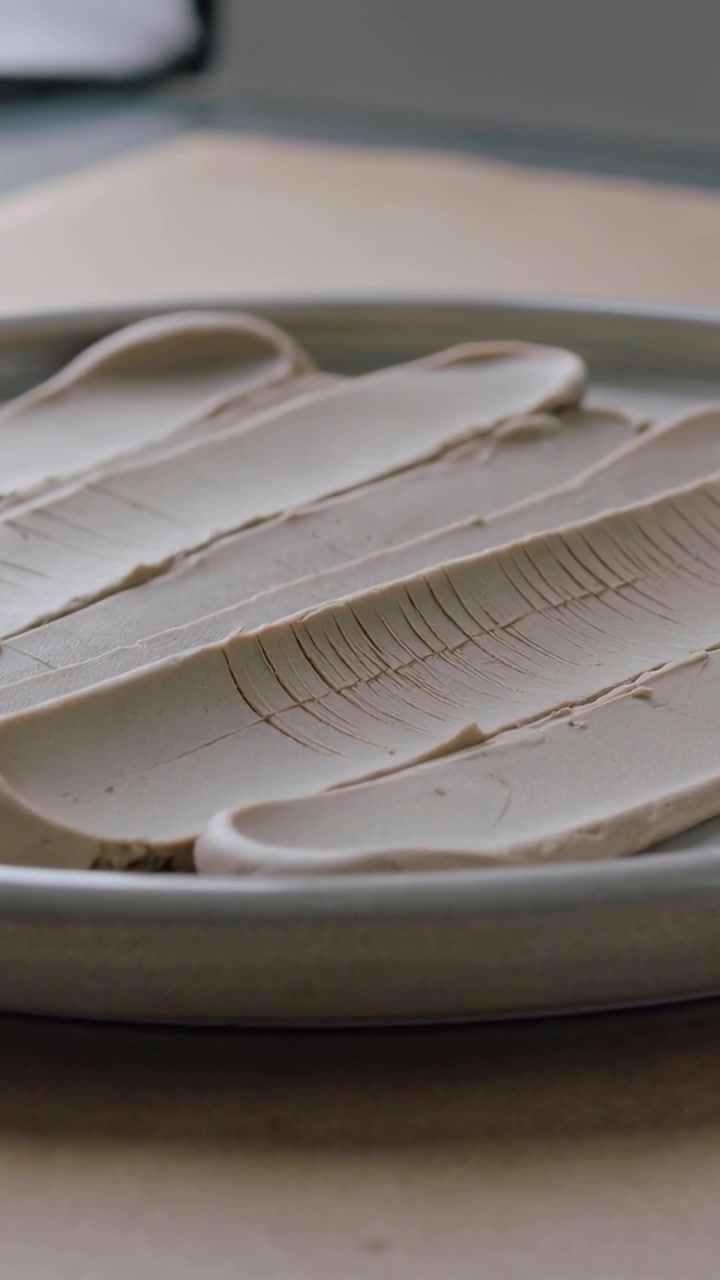 Vertical video: Shifting camera showing ceramic plate with beige smears by window, exposing cracks
