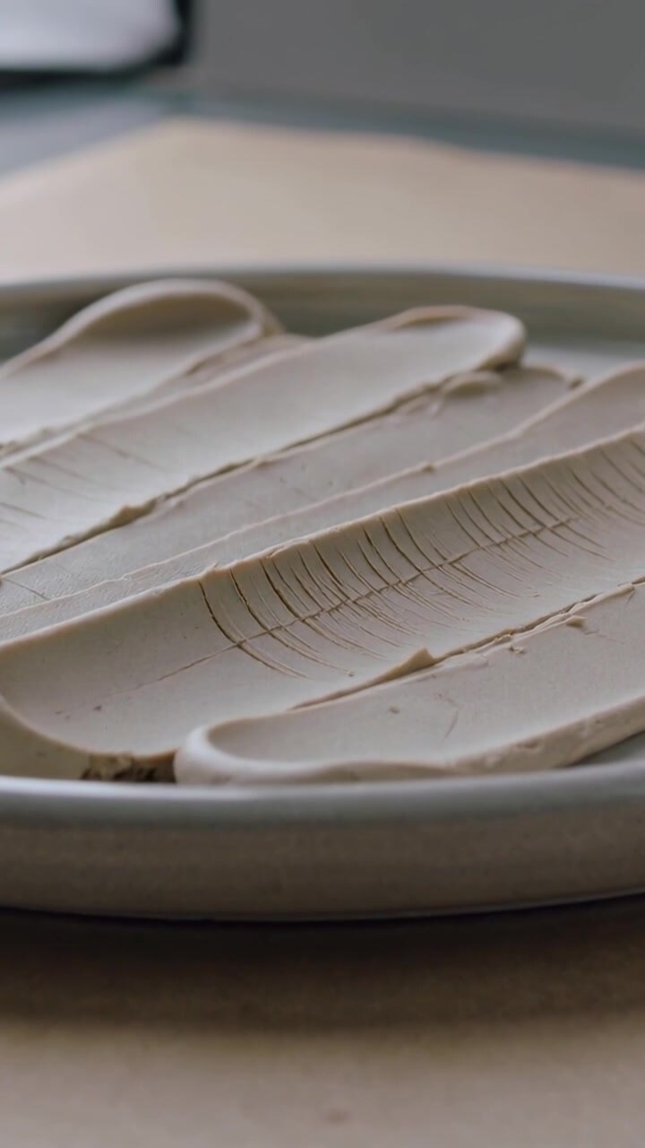 Vertical video: Shifting camera showing ceramic plate with beige smears by window, exposing cracks