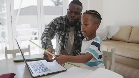 happy african american father and son using laptop, in slow motion