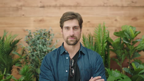 attractive young man portrait of handsome caucasian guy looking serious arms crossed smiling happy at camera plants background