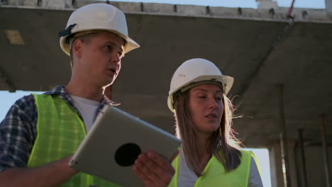 construction site team or architect and builder or worker with helmets discuss on a scaffold construction plan or blueprint or checklist