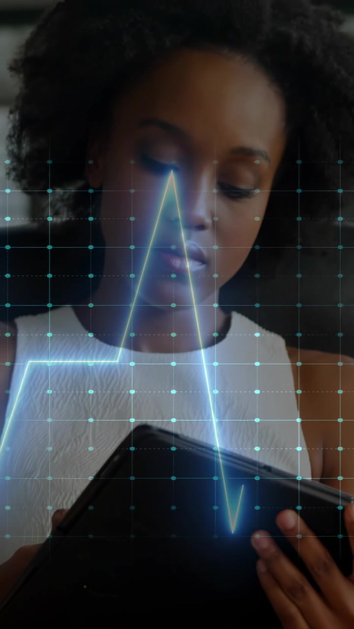 Vertical video: Woman tapping tablet at desk starting ECG line syncing to tap, tracking health data