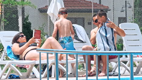 personas sentadas a la orilla de la piscina de un resort durante las vacaciones de verano