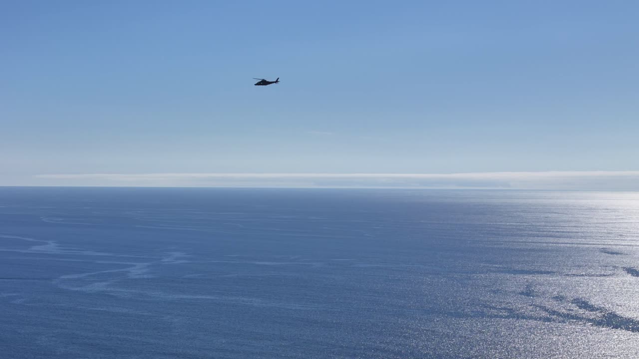 Helicopter flying over the ocean on sunny day