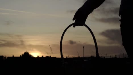 silhouette of woman carrying woven basket in countryside at sunset