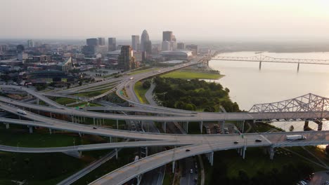 Vista-Aérea-Con-Vistas-A-Los-Puentes-Y-El-Paisaje-Urbano-De-Louisville,-Puesta-De-Sol-En-Kentucky,-Ee.uu.---Pan,-Tiro-De-Drones