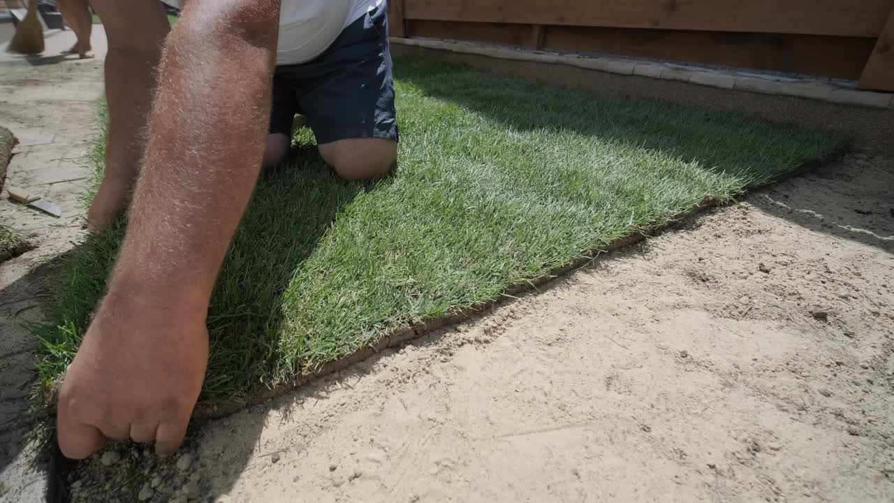 hombre colocando césped en el jardín del patio trasero para la instalación de césped y proyecto de jardinería, centrado en la mejora del hogar y el mantenimiento al aire libre para un césped fresco y verde en un patio residencial