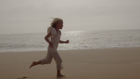 a happy girl runs on a beautiful beach at sunset.