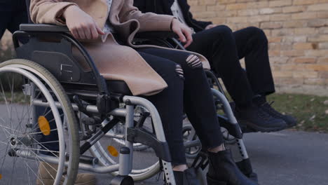 camera focuses on wheels of a wheelchair spinning on a walk in the street