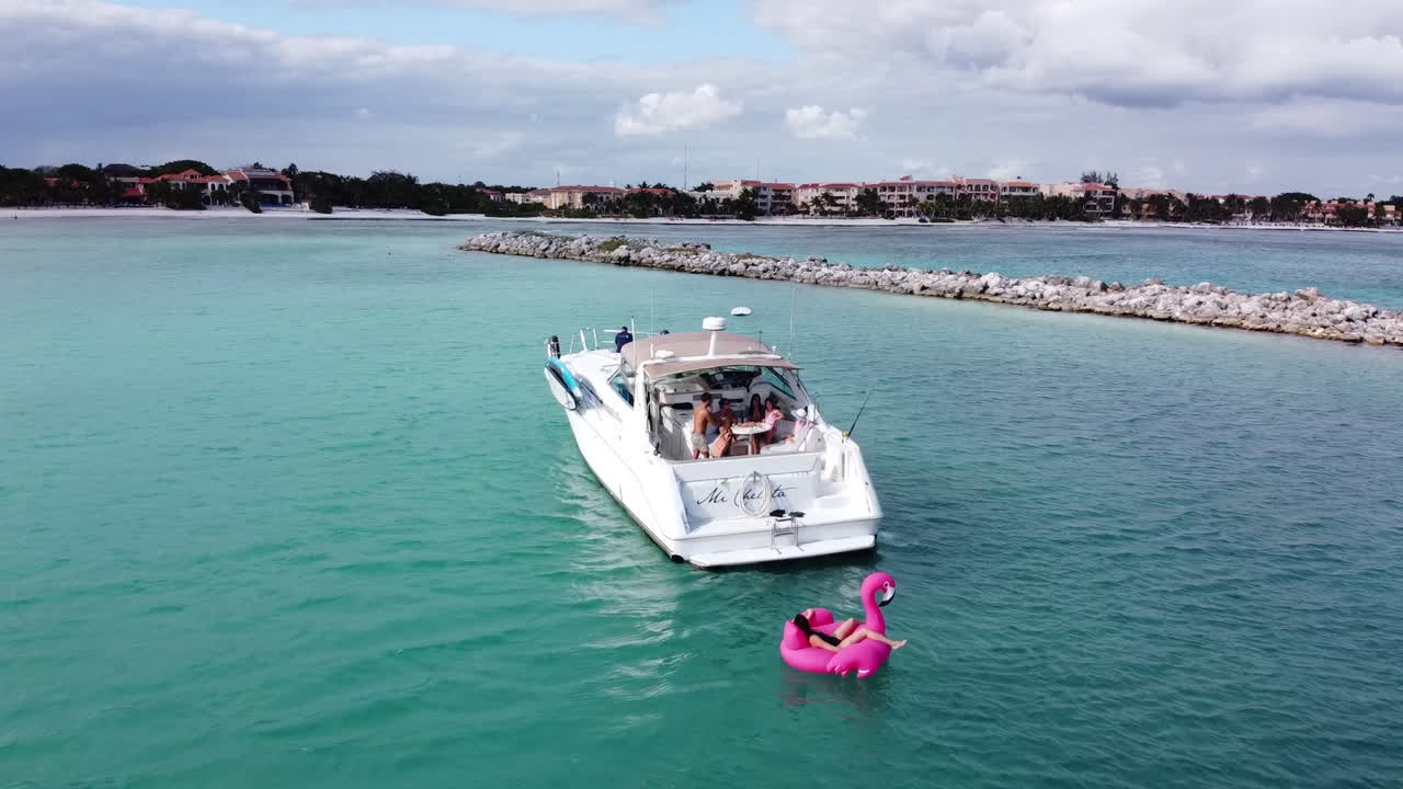 vista aérea de un yate blanco en puerto aventuras en la riviera maya, méxico tirando de un inflable unicornio y flamenco