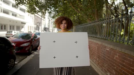 portrait of a woman holding empty billboard on sidewalk