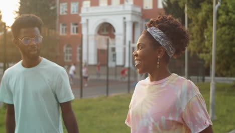 black man and woman walking outdoors in park and chatting