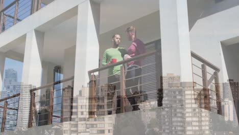 animation of cityscape over diverse male couple standing on balcony and drinking coffee