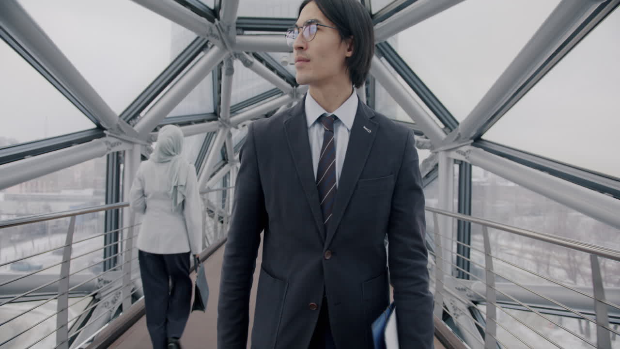 Businessman Walking Through a Modern Glass Bridge