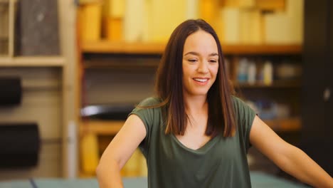 cerca de una mujer joven sonriendo mientras coloca una tabla y construye un marco de cama de madera dentro de un taller de carpintería profesional