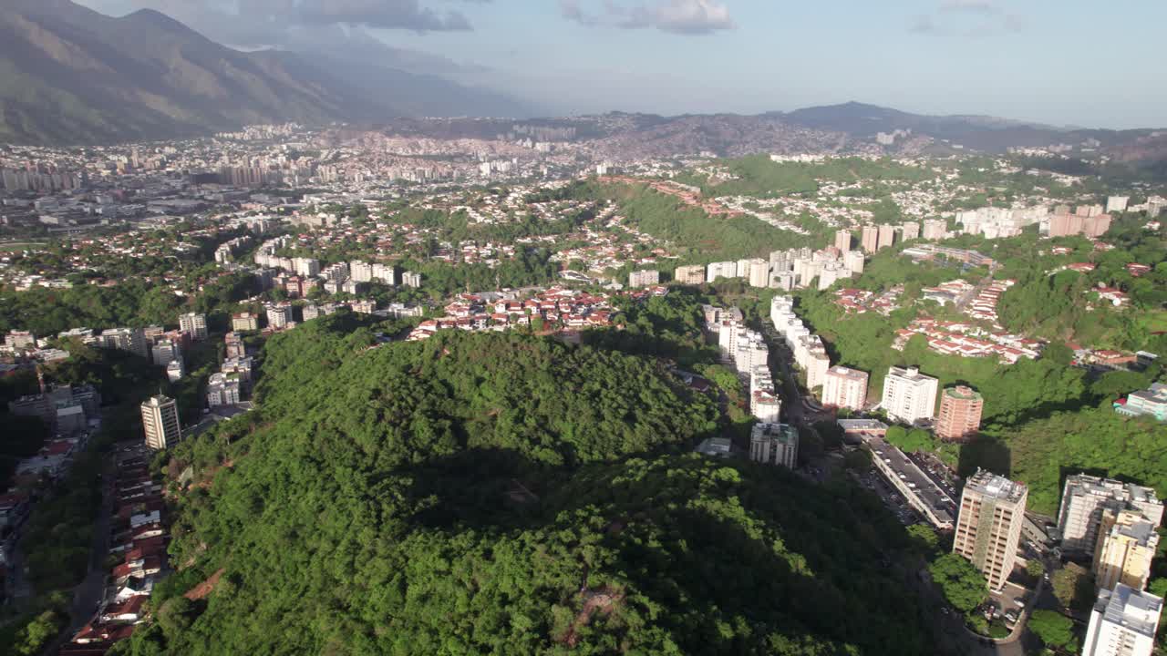 Aerial pan over residential area nestled in tropical green hills of Caurimare, in the Baruta Municipality Miranda State, vista cityscape of Venezuela's capital, Caracas